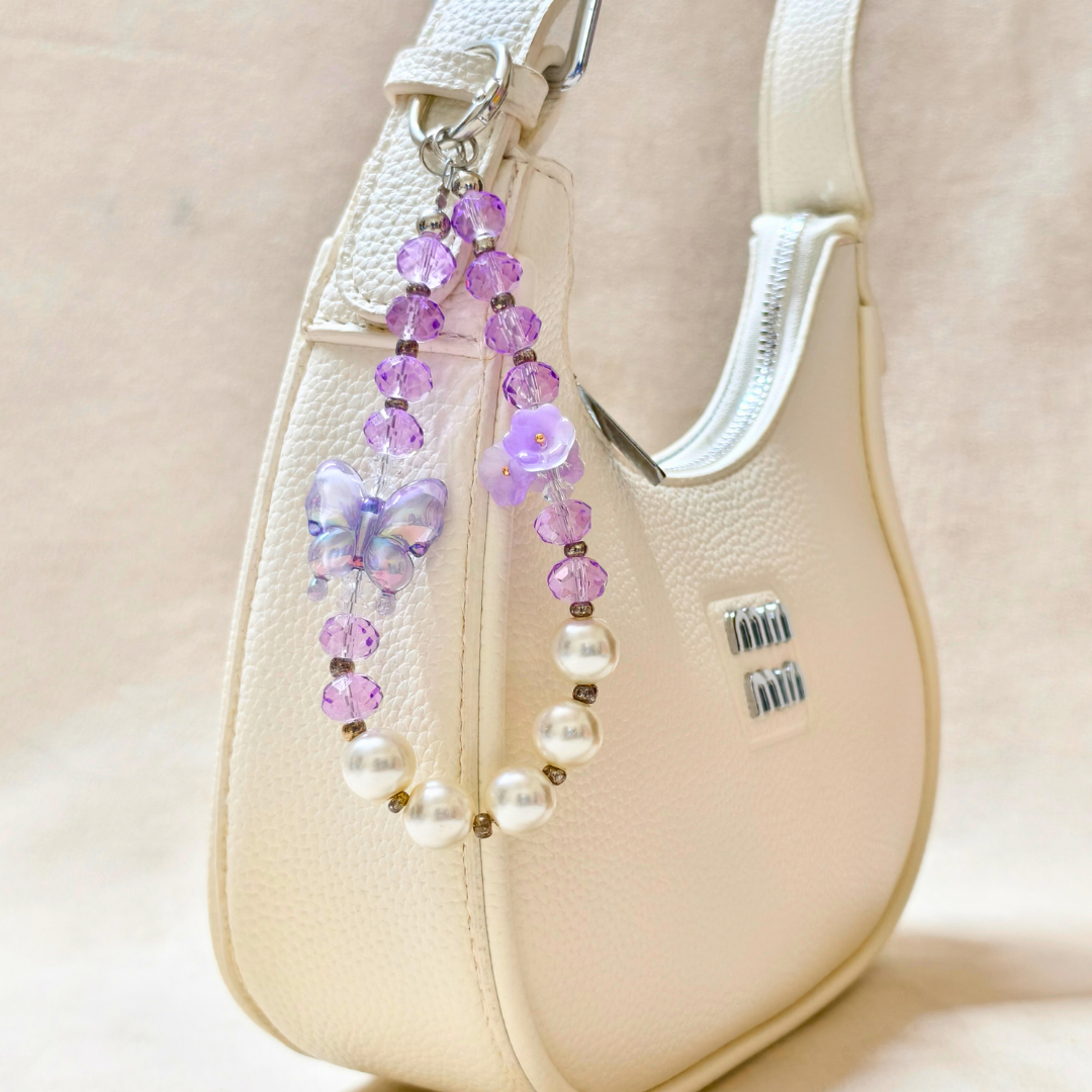 Beaded strap with purple and white beads on a beige handbag.