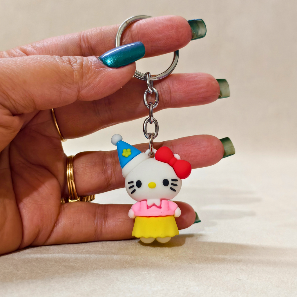 Hand holding a keychain with a cartoon character wearing a blue hat and yellow dress.