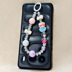 Phone case with decorative charm featuring colorful beads and animal figures on a beige background