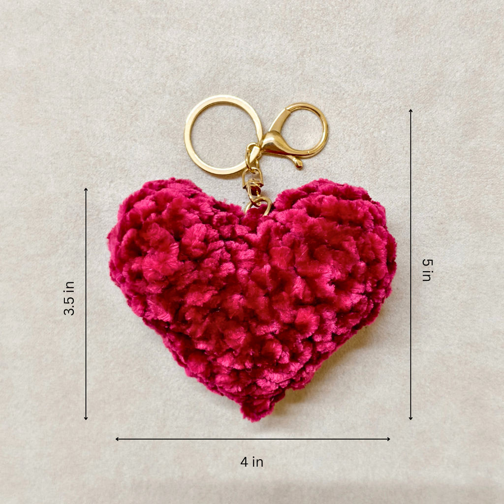 Pink heart-shaped keychain with gold clasp on a beige background with measurements.