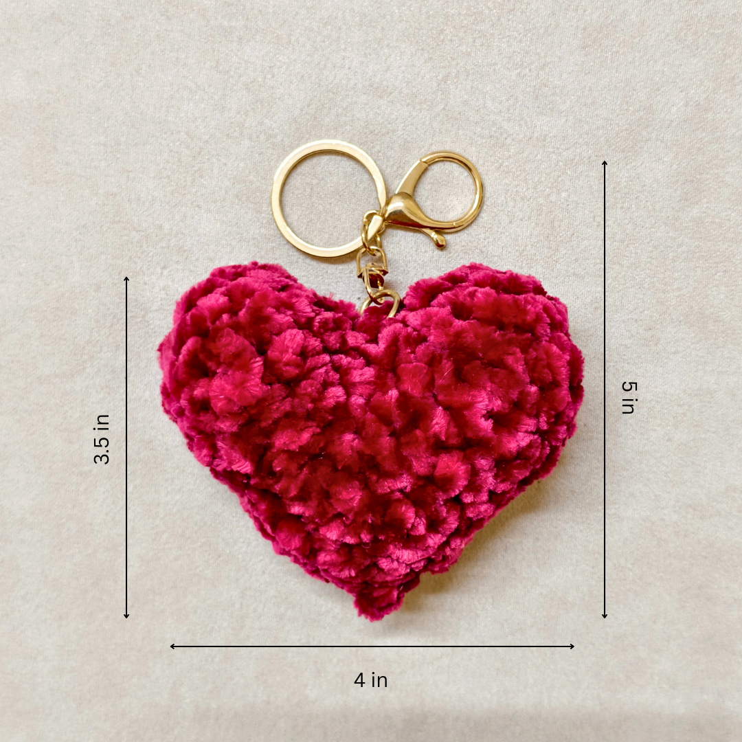 Pink heart-shaped keychain with gold clasp on a beige background with measurements.