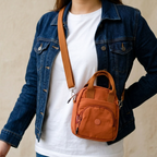 Person wearing a denim jacket with a brown crossbody bag on a beige background