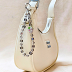Beige handbag with a decorative beaded strap on a light beige background