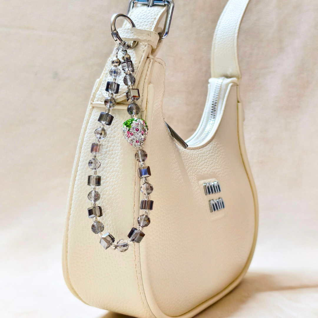 Beige handbag with a decorative beaded strap on a light beige background