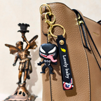 Keychain with a character design attached to a brown bag, next to a bronze statue.