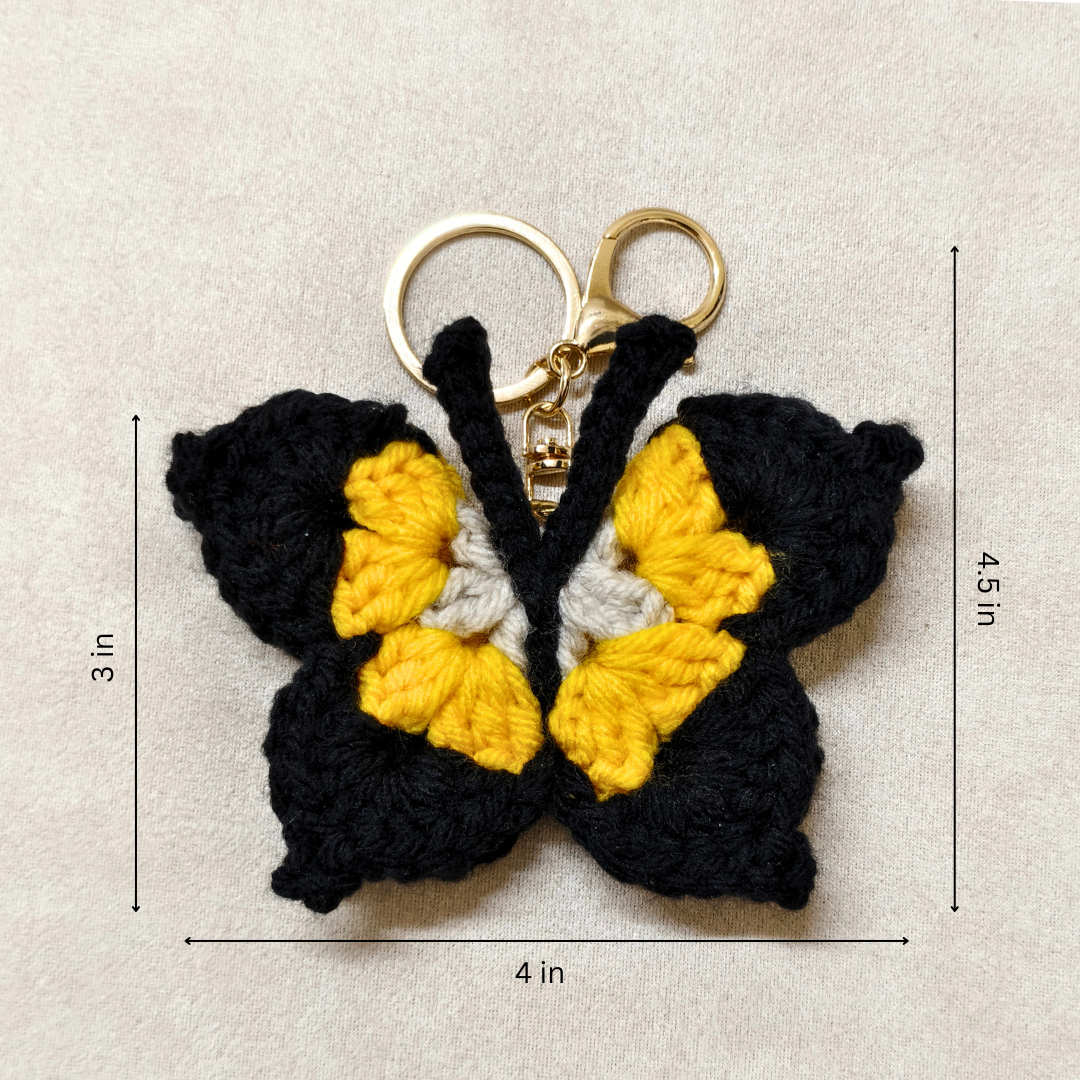 Crocheted butterfly keychain with measurements on a beige background