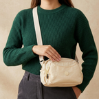 Model Carrying Cream Ivory Sling Bag In Front Of Beige Background.
