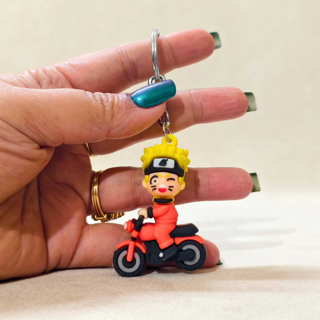 Keychain of a character riding a motorcycle held by a hand against a neutral background