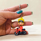 Keychain of a character riding a motorcycle held by a hand against a neutral background