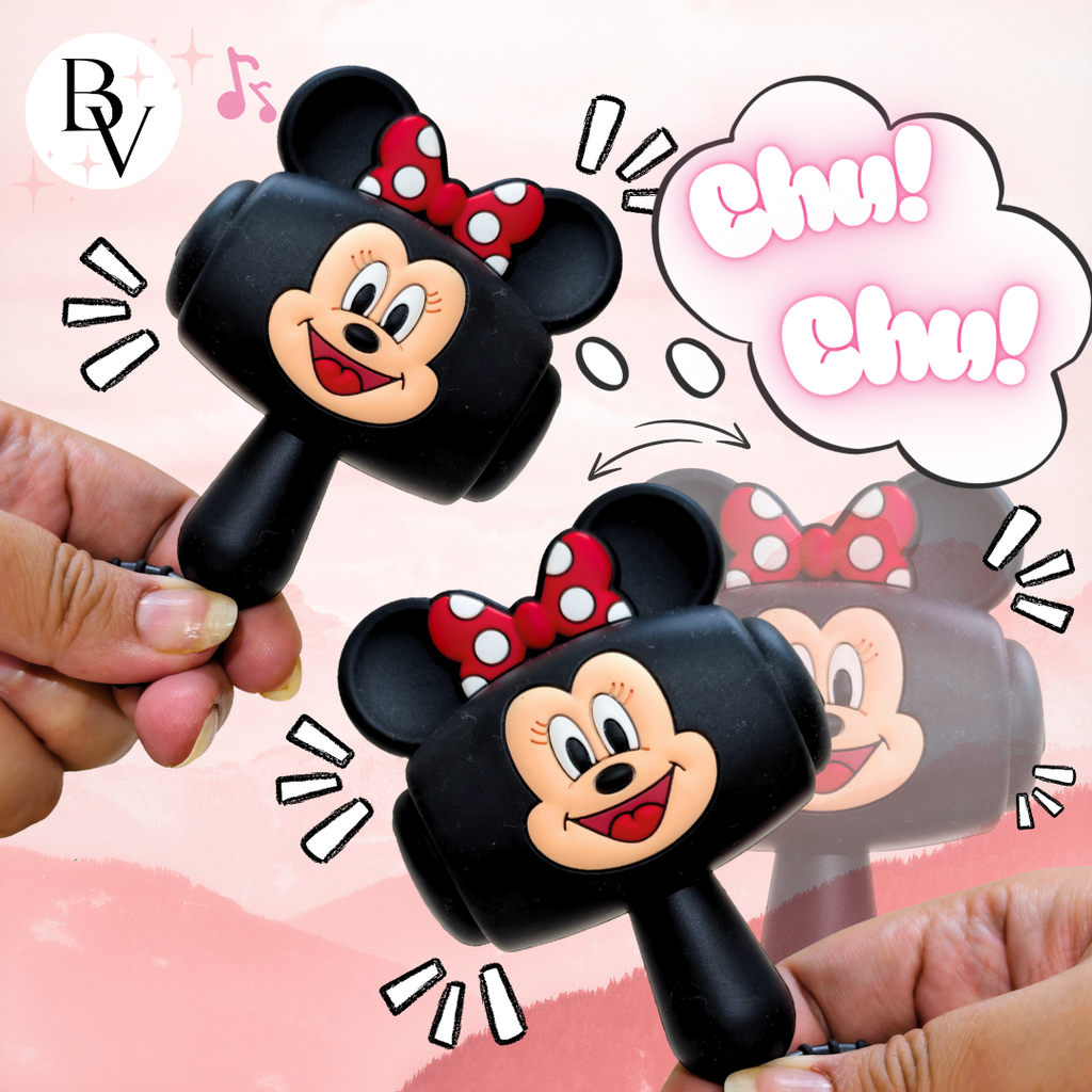 Two black plastic toy rammers shaped like Minnie Mouse's head and bow, held by hands against a pink illustrated background with cartoon speech bubbles and a 'BV' logo in the top left.