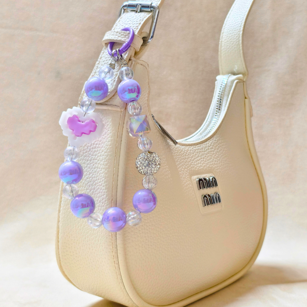 Beige handbag with a decorative beaded strap featuring purple and pink beads.