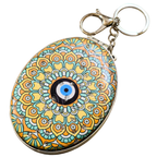 An oval-shaped evil eye keychain featuring a colorful mandala pattern in yellow, teal, orange, and black, with a silver-tone metal clasp and keyring.
