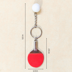 A ping-pong themed keychain featuring a red paddle and white ball, with black dimension lines and text showing measurements of 5.5 inches, 2.