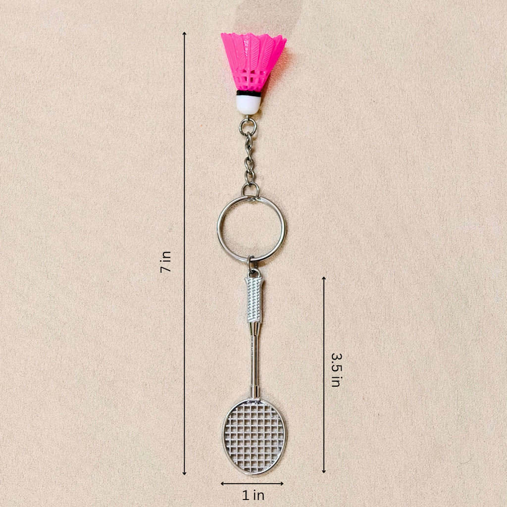  silver metal badminton racket keychain with a small pink and white plastic shuttlecock attached, showing measurements against a plain beige background.