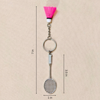  silver metal badminton racket keychain with a small pink and white plastic shuttlecock attached, showing measurements against a plain beige background.