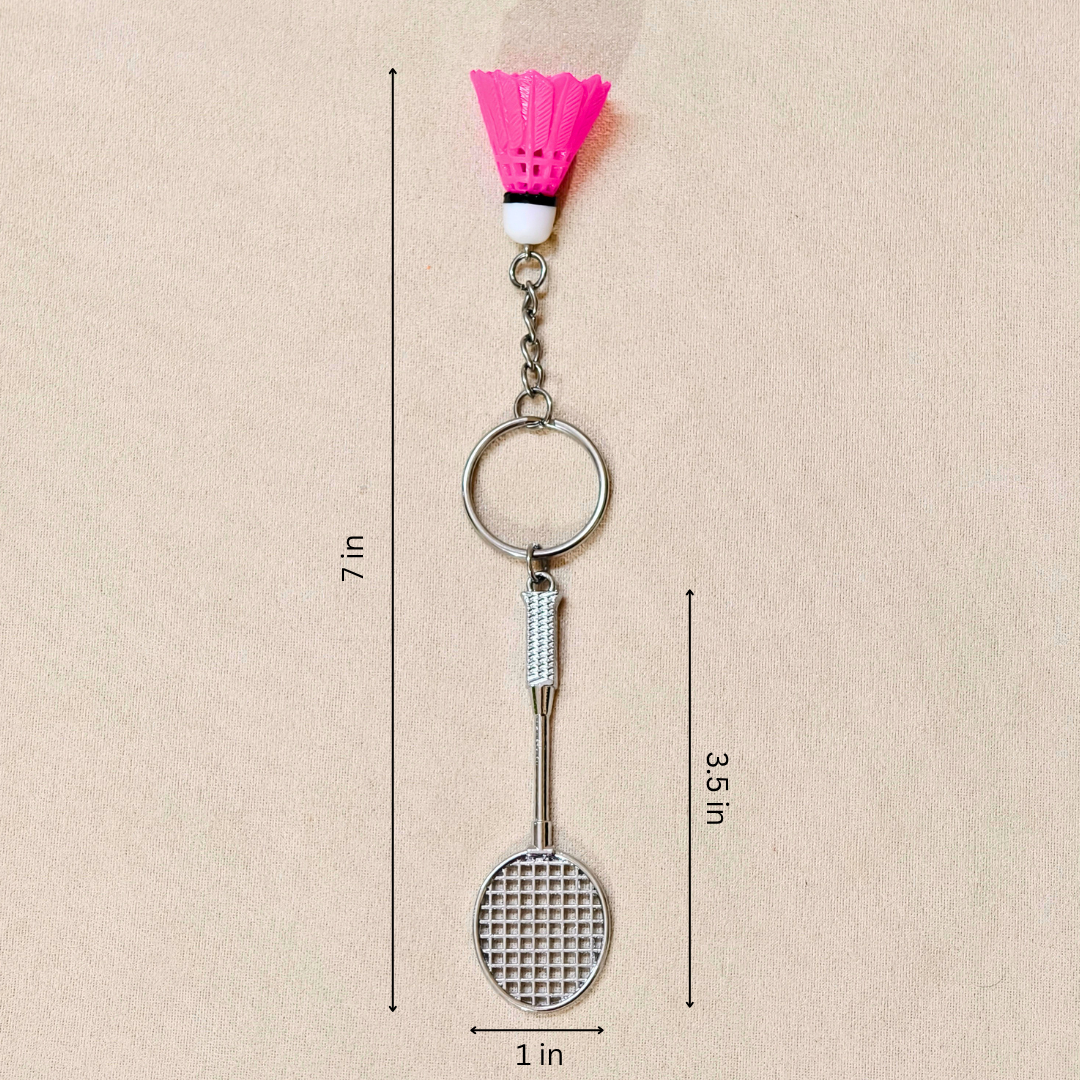  silver metal badminton racket keychain with a small pink and white plastic shuttlecock attached, showing measurements against a plain beige background.