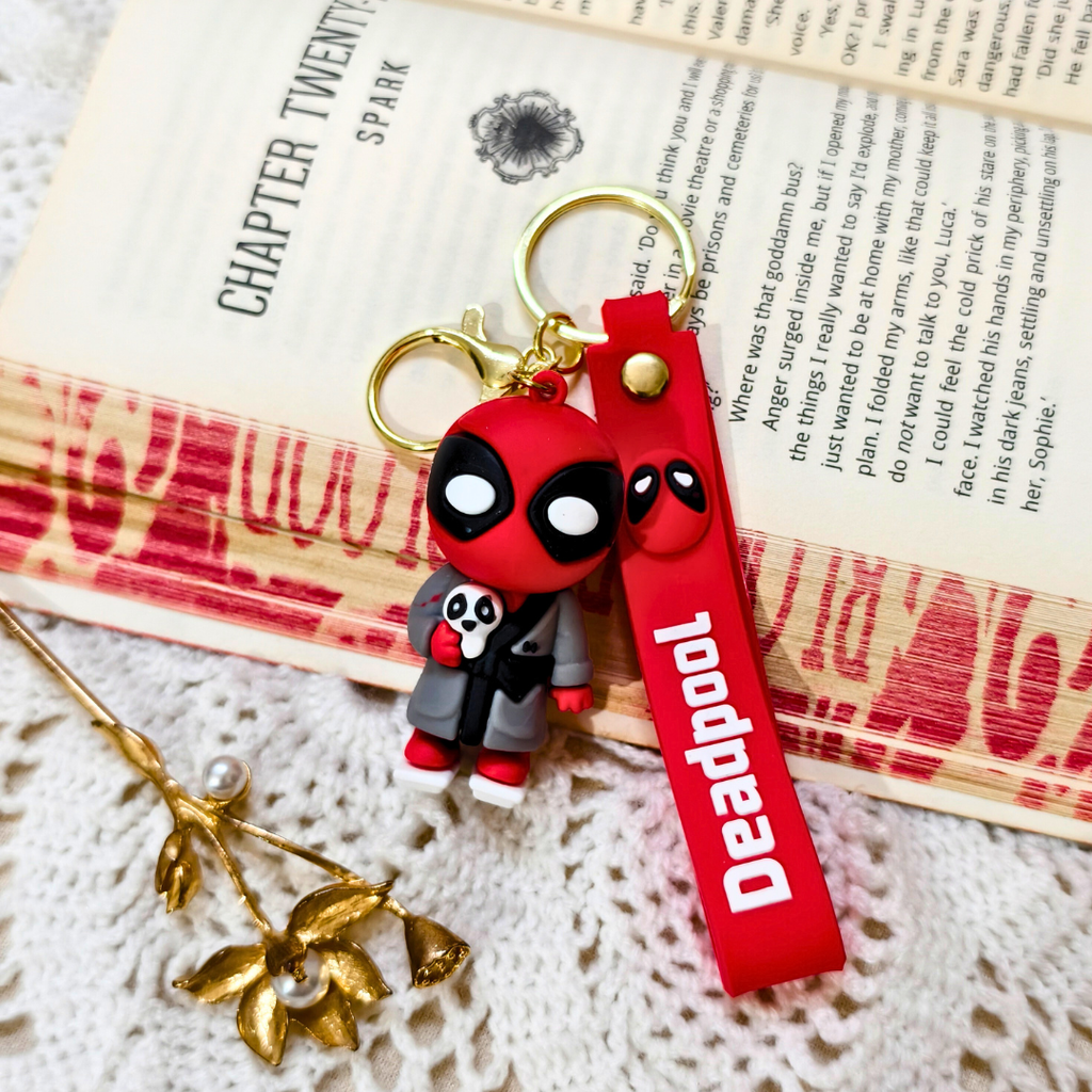 Deadpool keychain with red strap on a textured surface
