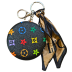 A Louis Vuitton monogram mini coin purse keychain in black textured leather, featuring a colorful floral monogram pattern and a brown and black silk scarf attached to a silver-tone clasp and split ring.