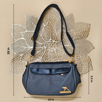 Blue handbag with gold accents on a beige background with measurements