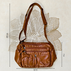 Brown leather handbag with measurements on a textured white background
