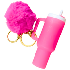 A bright pink silicone tumbler keychain with a matching pink faux fur pom-pom, gold split rings, and a white lid, shown on a plain white background.