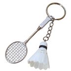 A novelty keychain shaped like a badminton racket with a white shuttlecock charm, attached to a silver metal key ring and chain.