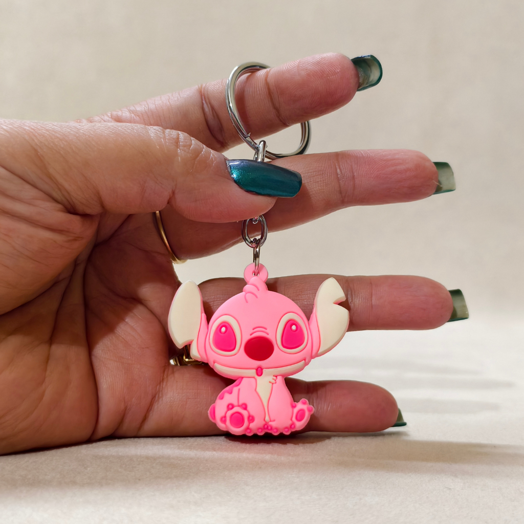 Hand holding a pink cartoon character keychain against a neutral background