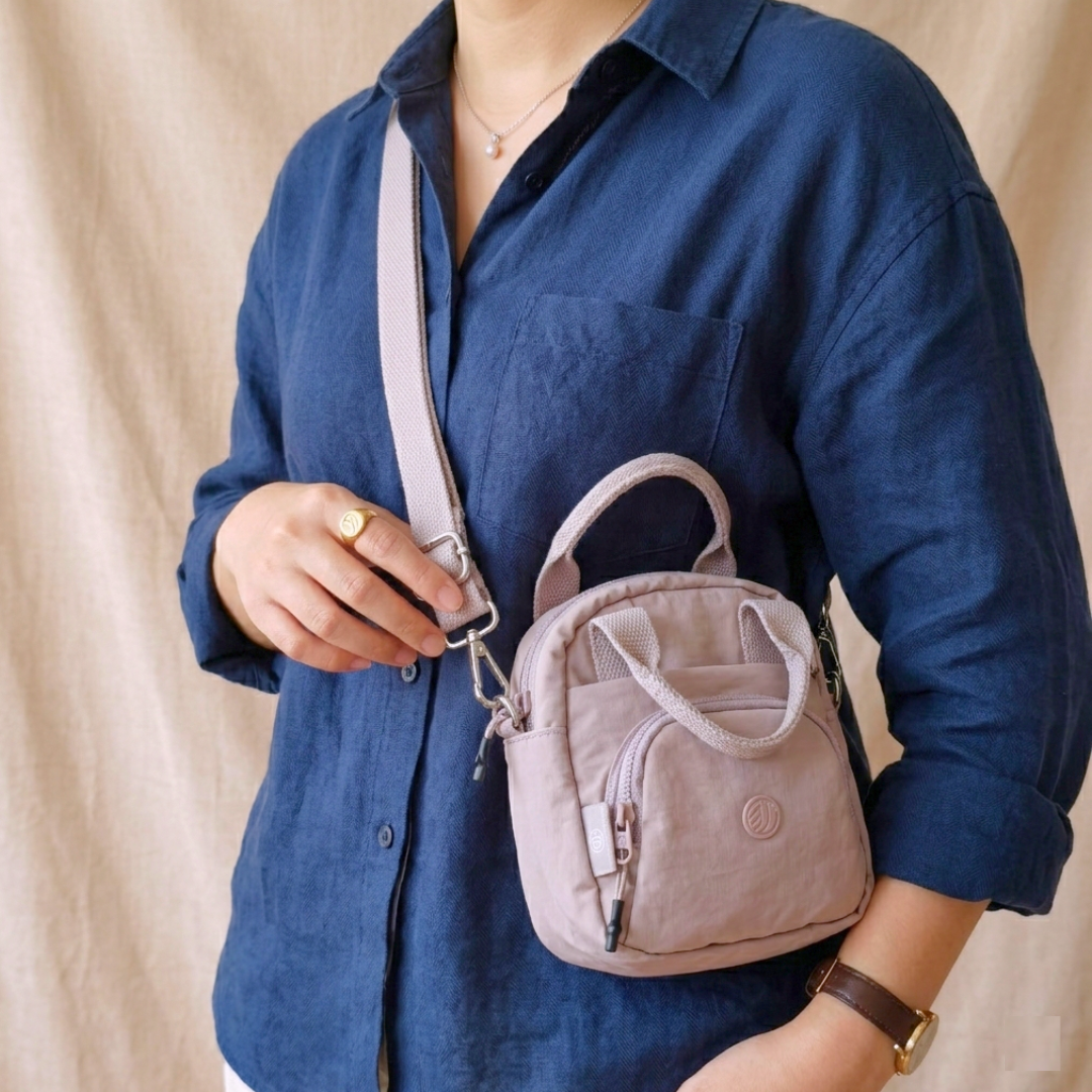 Person holding a beige backpack with a plain background