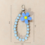 Blue Flower Phone Charm With Measurements In Front Of Beige Background.
