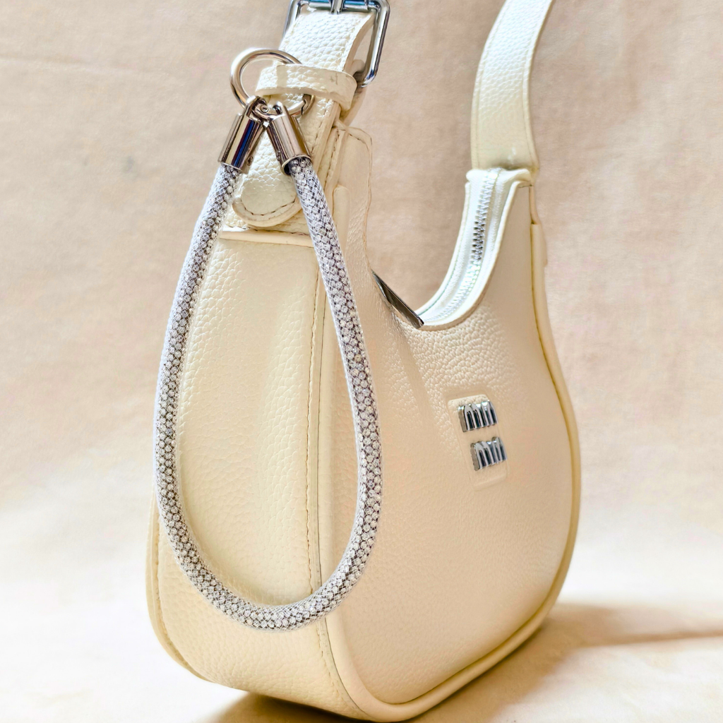 Beige handbag with a decorative chain detail on a beige background