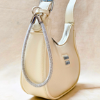 Beige handbag with a decorative chain detail on a beige background