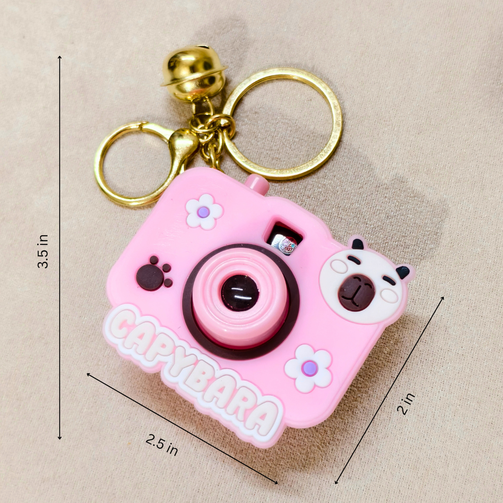 Pink capybara-shaped camera keychain with measurements on a beige background