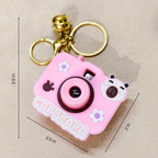 Pink capybara-shaped camera keychain with measurements on a beige background