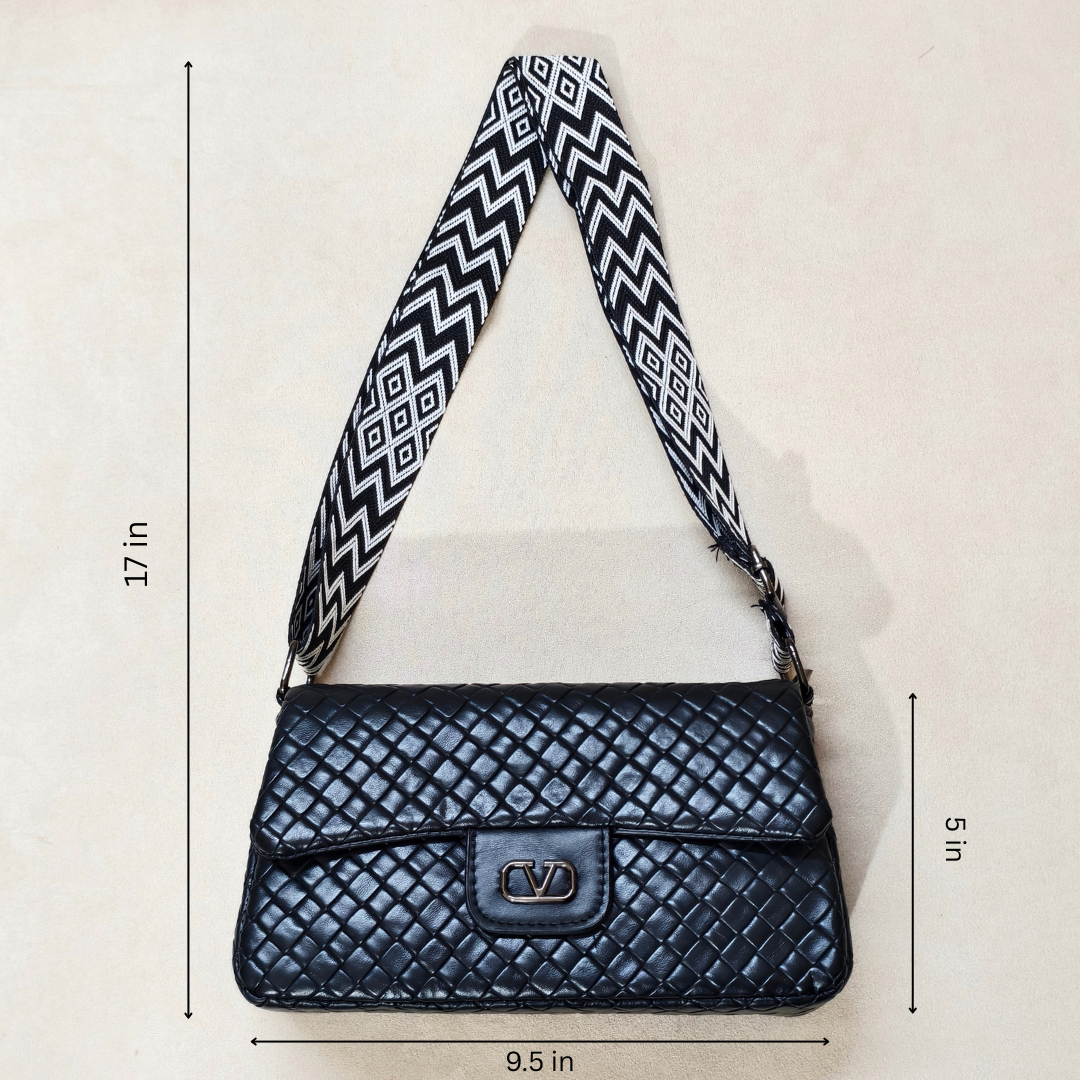Black quilted handbag with a patterned strap on a light beige background, showing measurements.