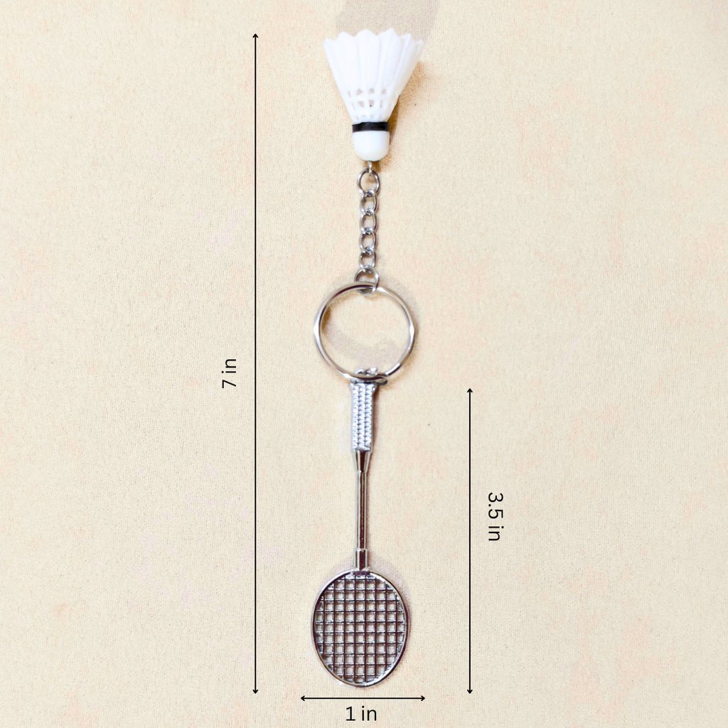 A badminton-themed keychain featuring a miniature silver badminton racket and shuttlecock, shown with dimension lines indicating a height of 7 inches, width of 1 inch, and 3.5 inch spacing on a light beige background.