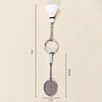 A badminton-themed keychain featuring a miniature silver badminton racket and shuttlecock, shown with dimension lines indicating a height of 7 inches, width of 1 inch, and 3.5 inch spacing on a light beige background.