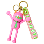 A pink cartoon monster keychain with gold metal key rings and a translucent pink strap that reads 'MONSTER' in green letters, shown on a plain white background.