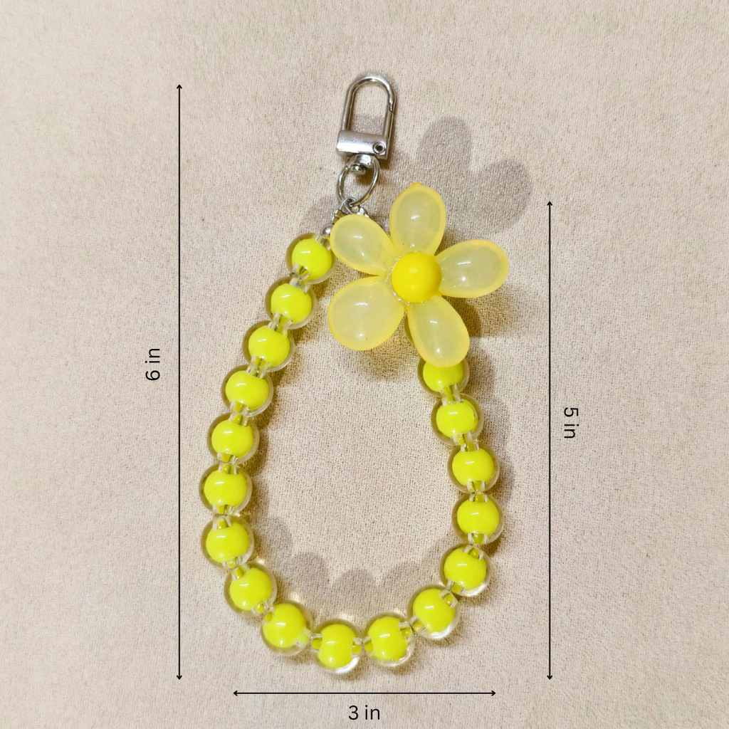 Yellow flower keychain with measurements on a beige background