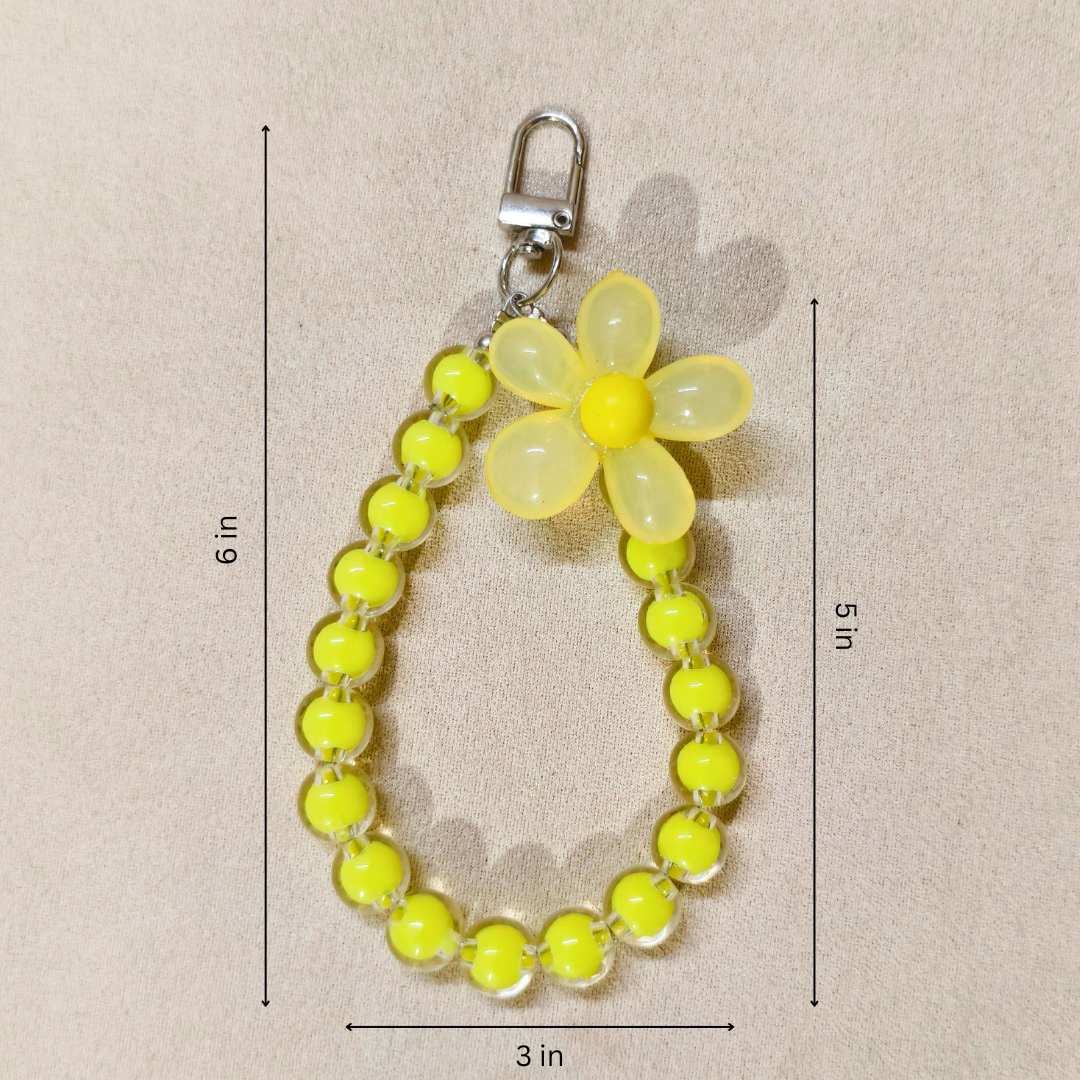 Yellow flower keychain with measurements on a beige background