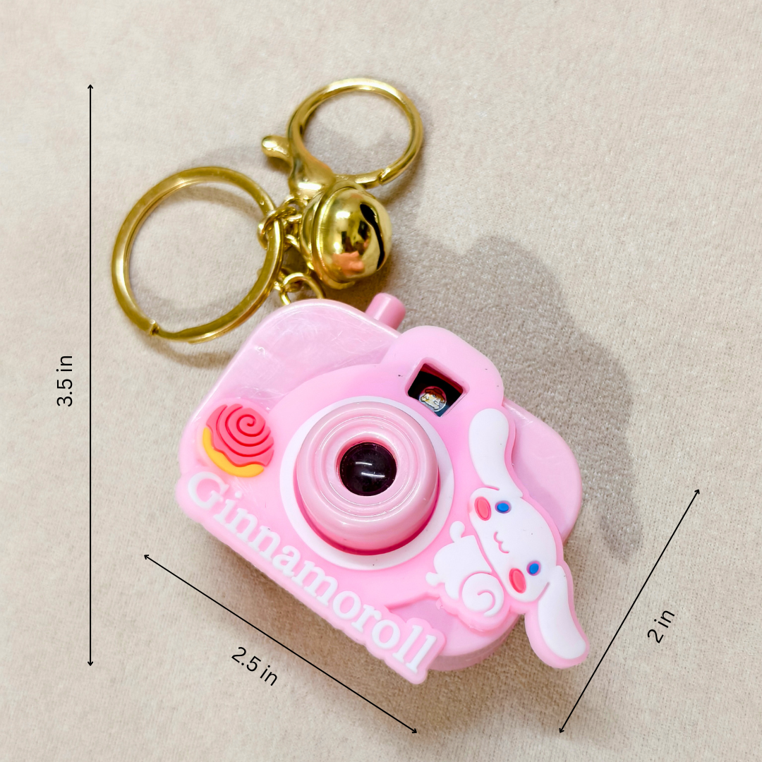 Pink camera-shaped keychain with dimensions on a beige background