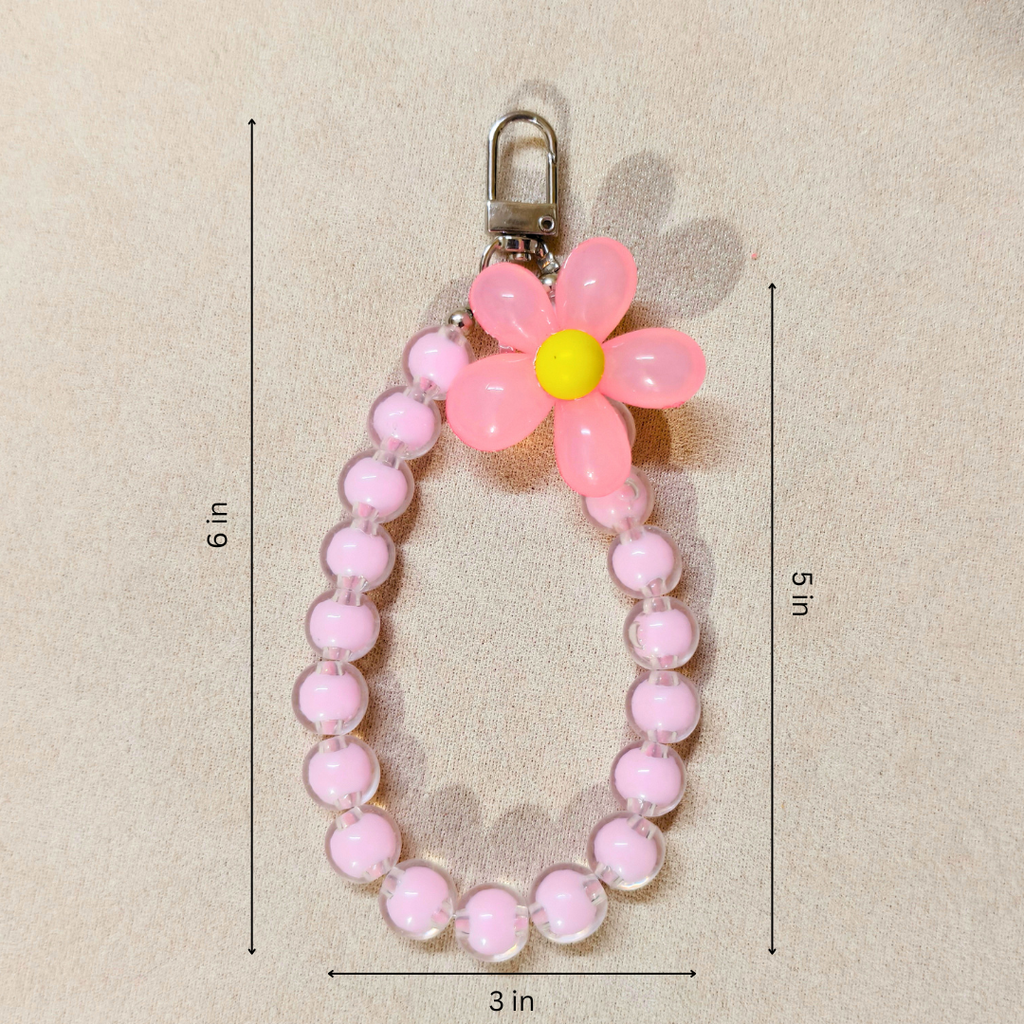 Pink beaded keychain with a flower-shaped charm on a beige background