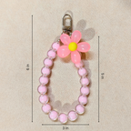 Pink beaded keychain with a flower-shaped charm on a beige background