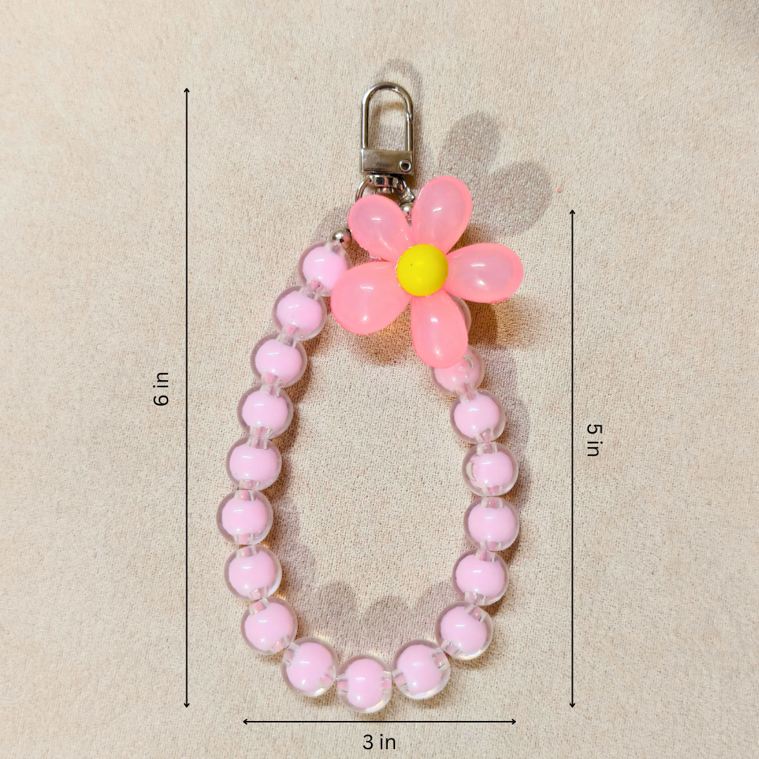 Pink beaded keychain with a flower-shaped charm on a beige background
