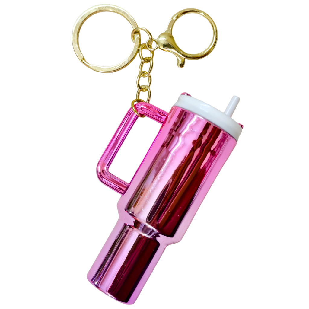 A novelty keychain shaped like a metallic pink insulated tumbler with a handle, gold keyring, and white straw cap, shown on a plain white background.