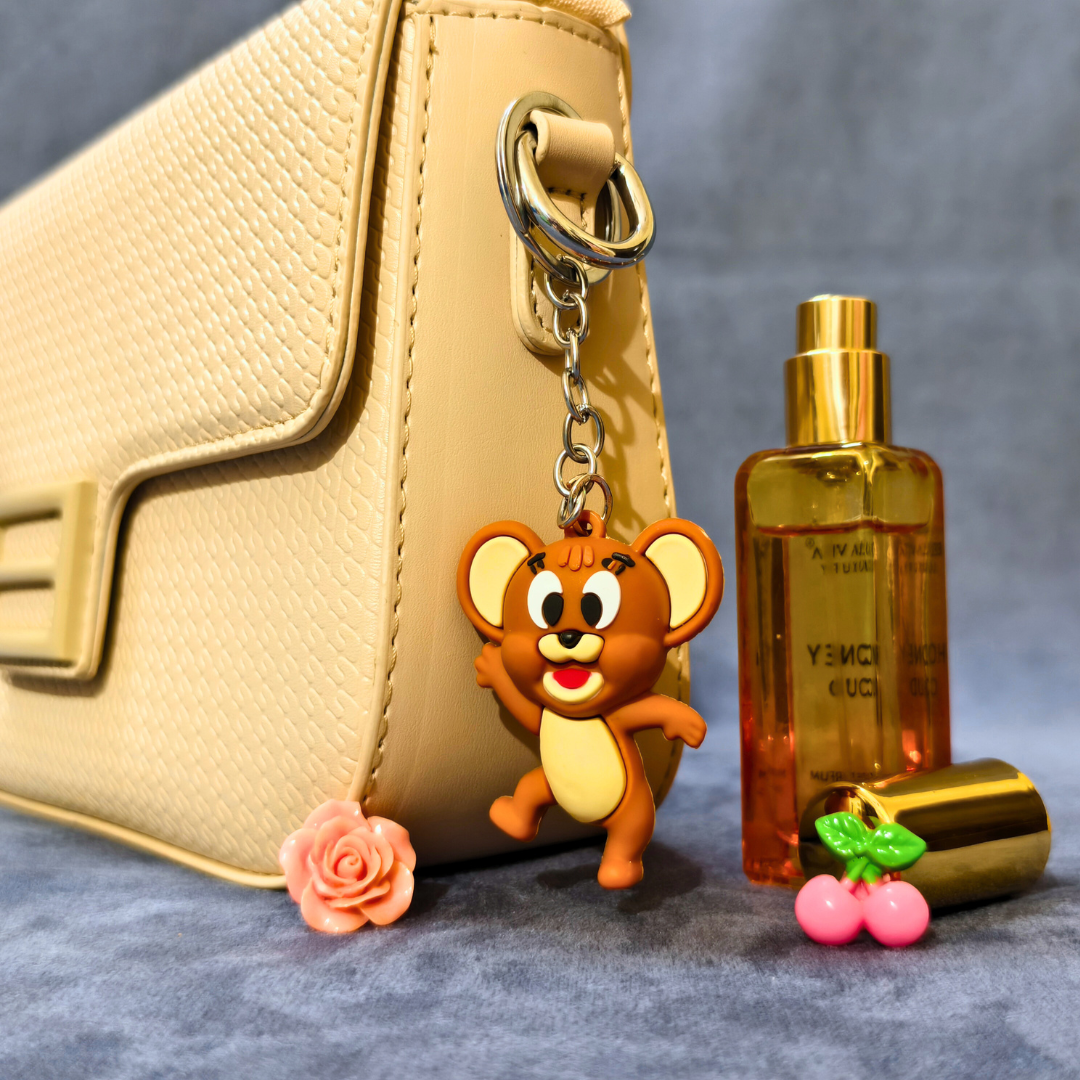 Beige handbag with a cartoon mouse keychain, orange bottle, and pink cherry on a gray surface.