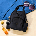 Black backpack on a blue denim surface with sunglasses and a bottle nearby