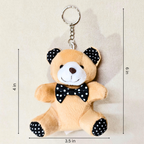 A plush teddy bear keychain with a black and white polka dot bow tie, black polka dot ears and feet, and a silver key ring, shown with dimension lines indicating 4 in height, 6 in overall height, and 3.5 in width.