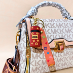 Brown cylinder keychain on a white printed purse in front of a beige background.