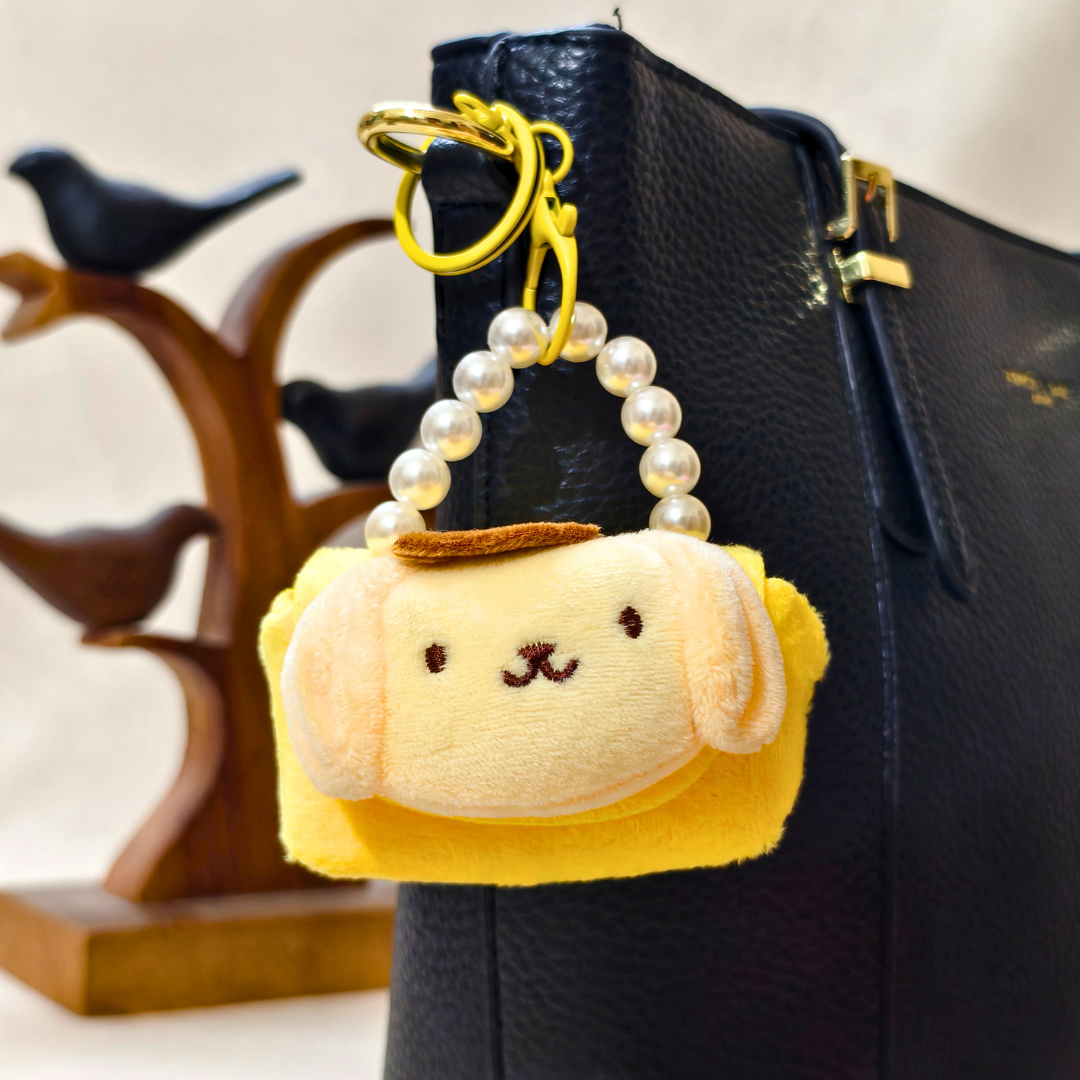 Plush keychain attached to a black bag with a blurred background