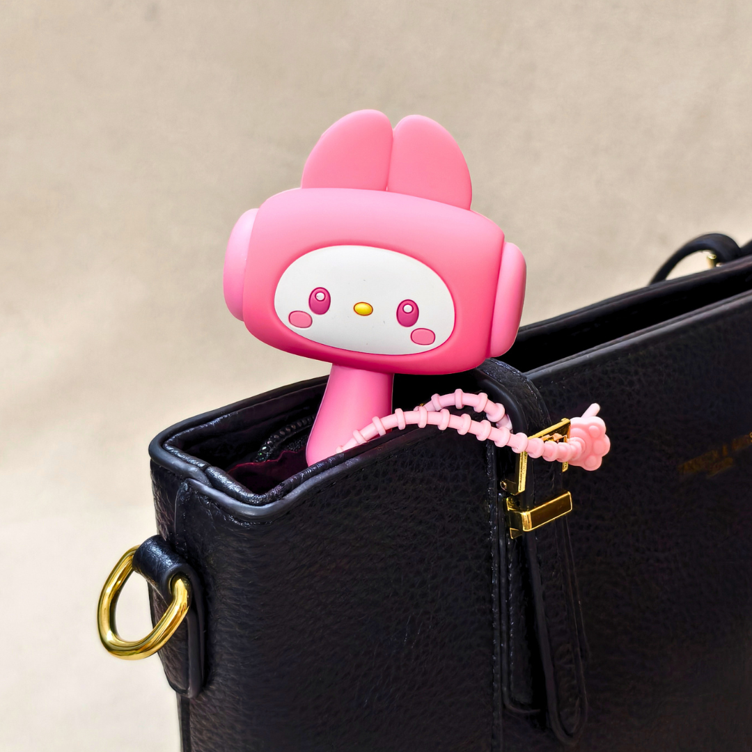 Pink cartoon character keychain attached to a black handbag